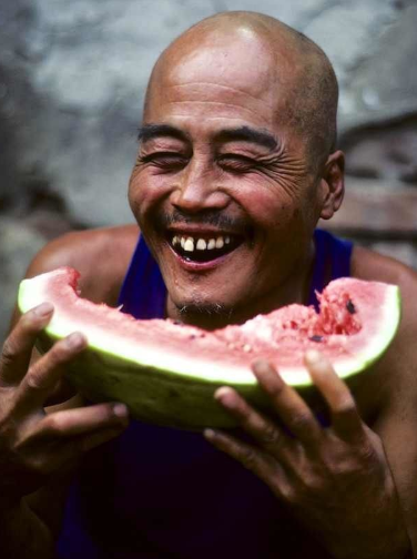 一位正在吃西瓜的大叔,可以看到这位大叔看到照相机在拍他的时候,笑
